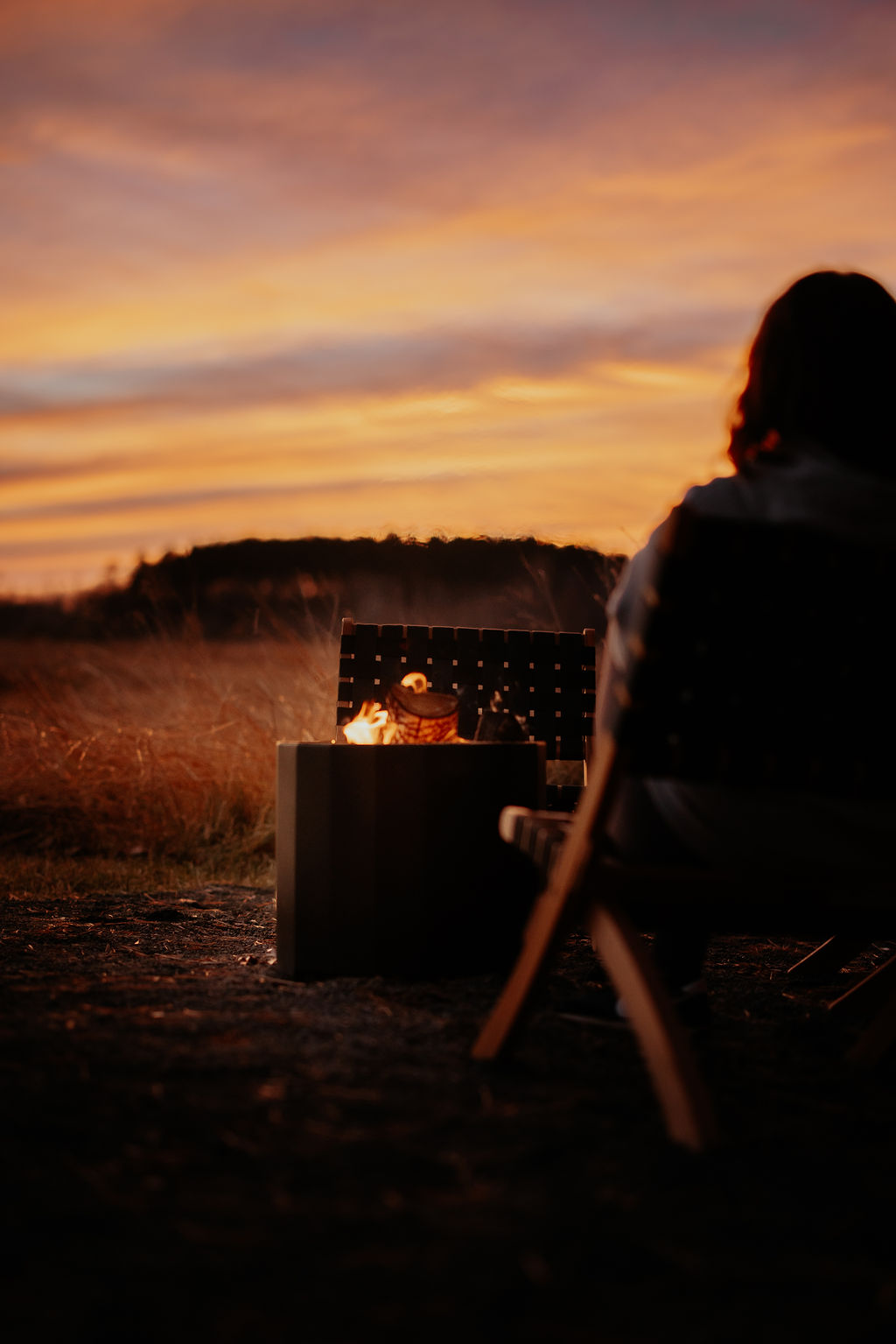Women sitting by a crackling fire watching the golen hour sunset over the prairie at Sweetbriar Ridge